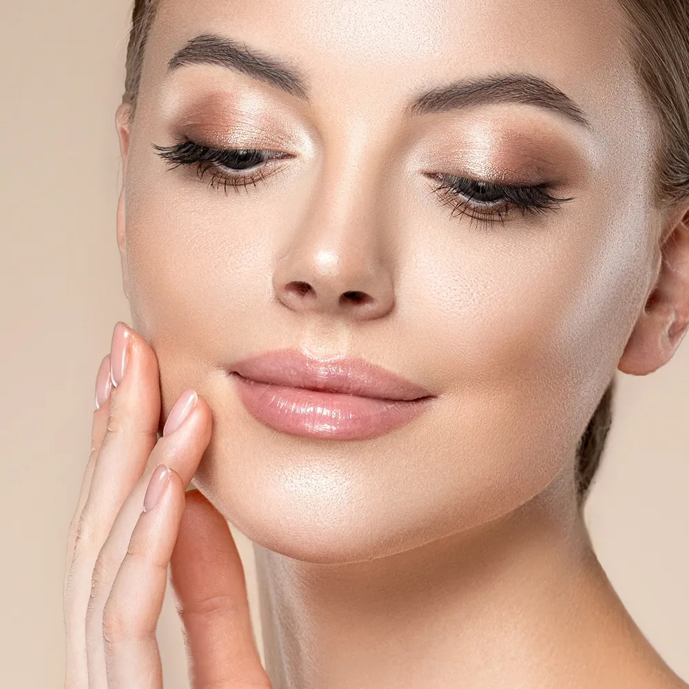Close-up of a woman touching the skin on her face.