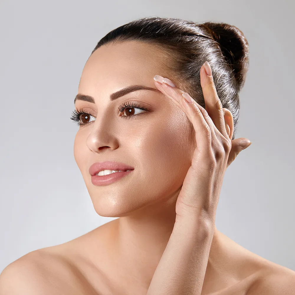 Close-up of a woman touching the skin on her face.