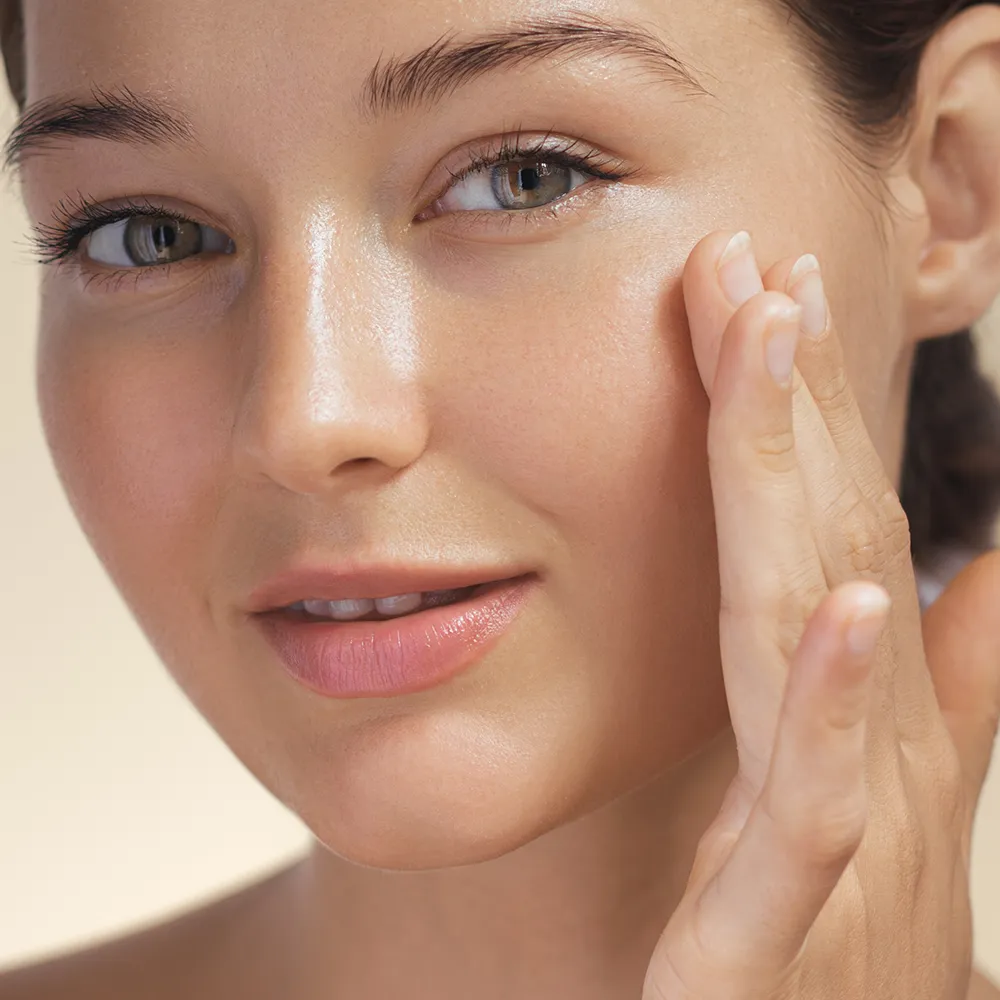 Close-up of a woman touching the skin on her face.