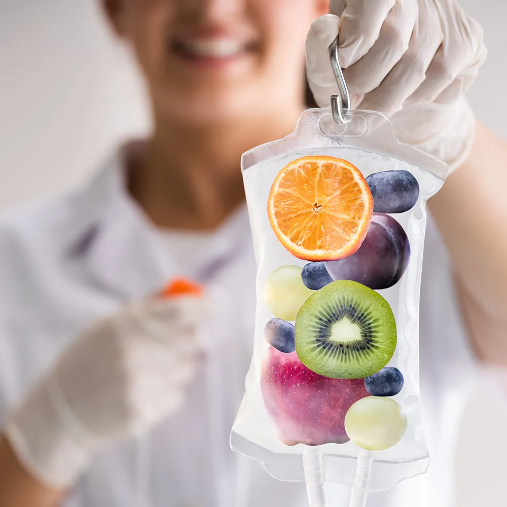 A doctor holding an IV bag with a fruit illustration on it.