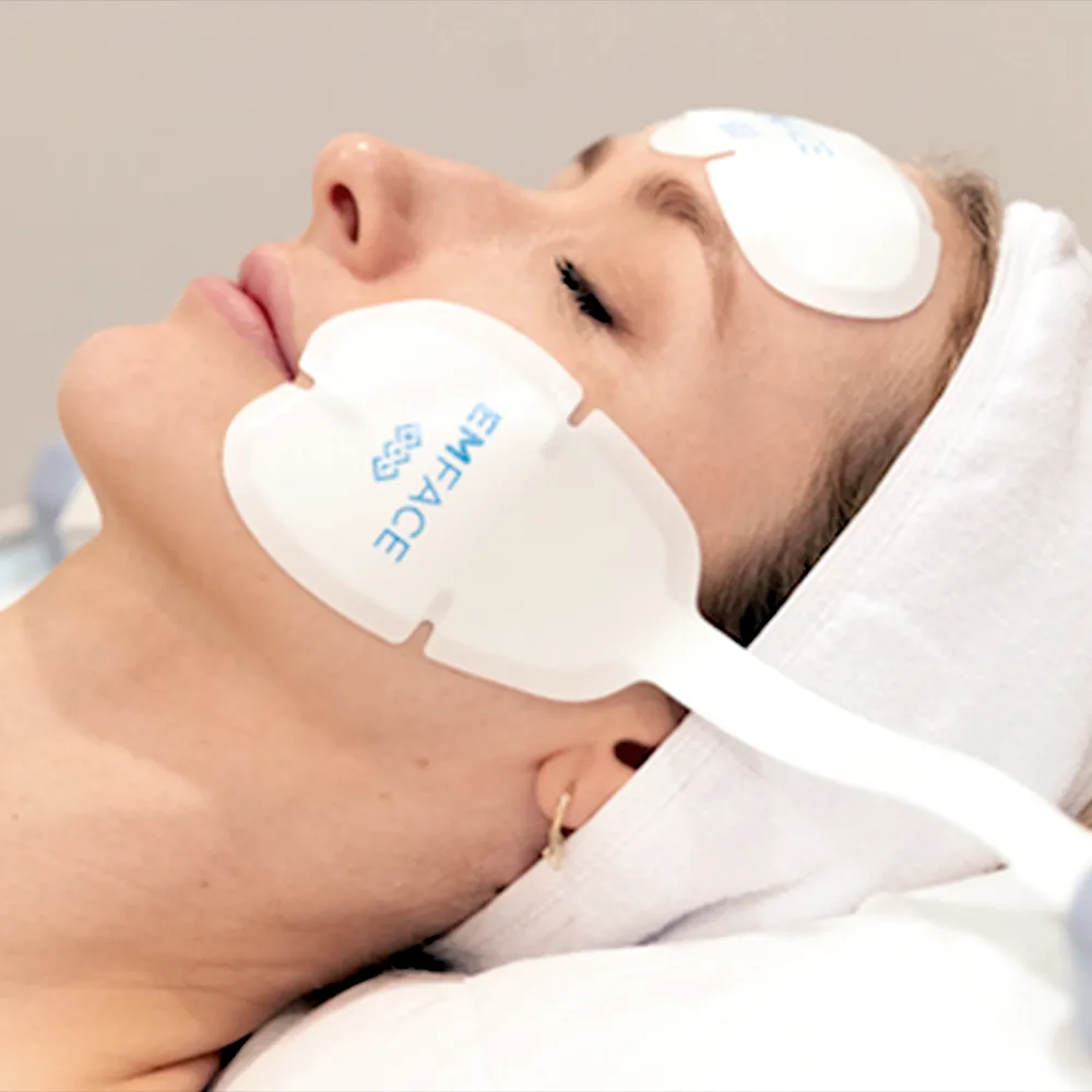 A woman receiving an EMFACE facial treatment.