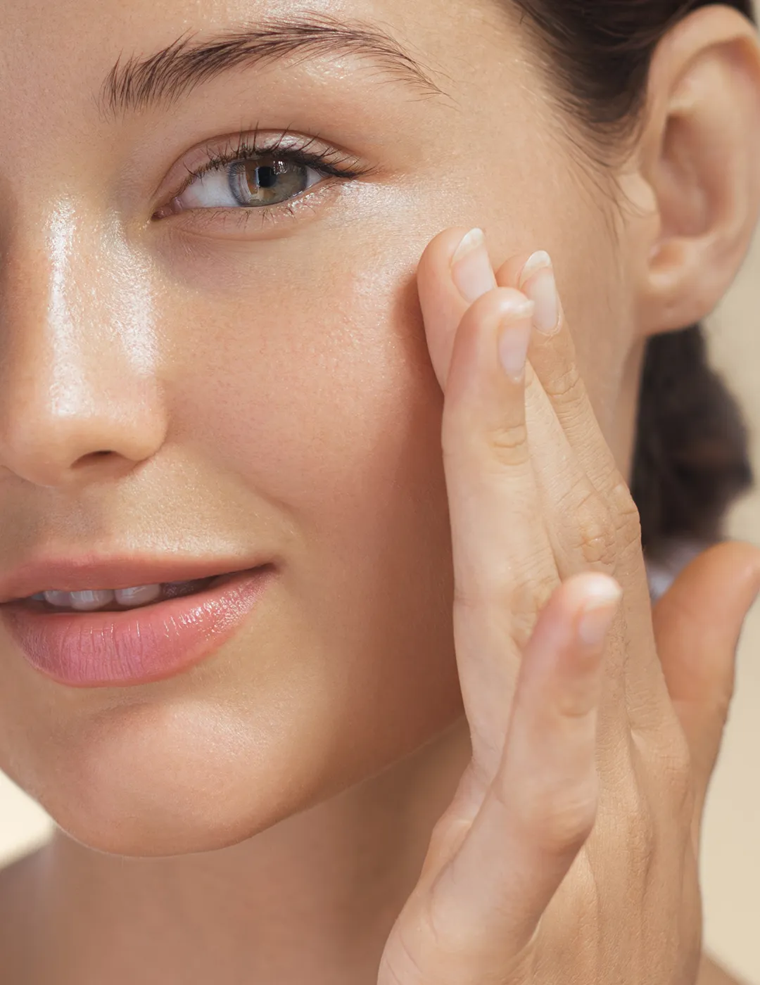 Close-up of a woman touching the skin on her face.