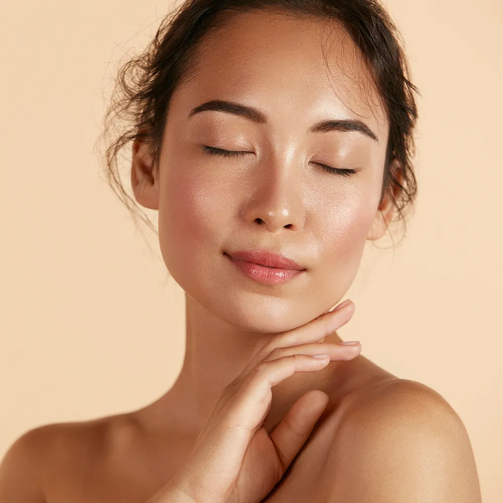 Close-up of a woman touching the skin on her face.