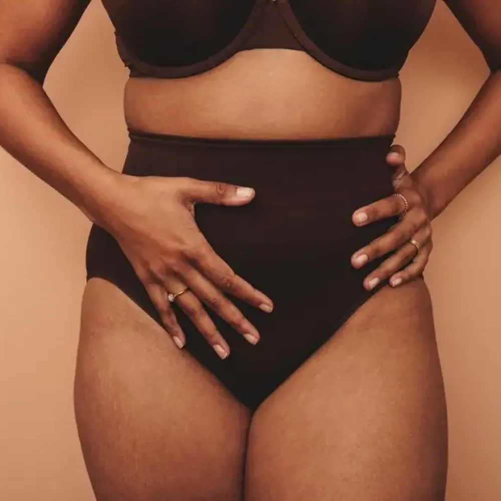 A woman wearing underwear touching her body.